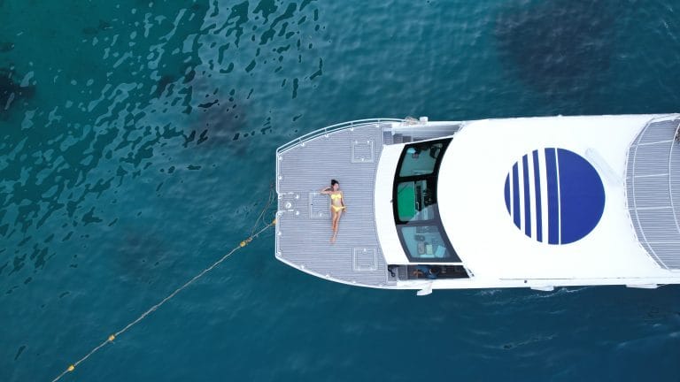 Aerial view of a white speed catamaran crossing deep blue water near Phuket
