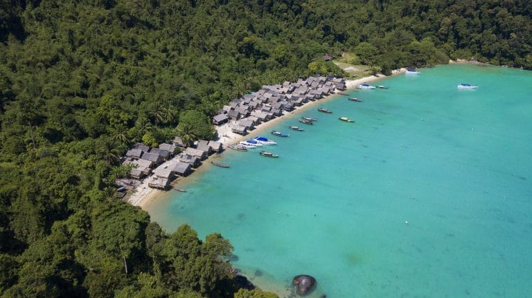 Aerial view of a sheltered turquoise bay, beach and visitor facilities in the Surin Islands