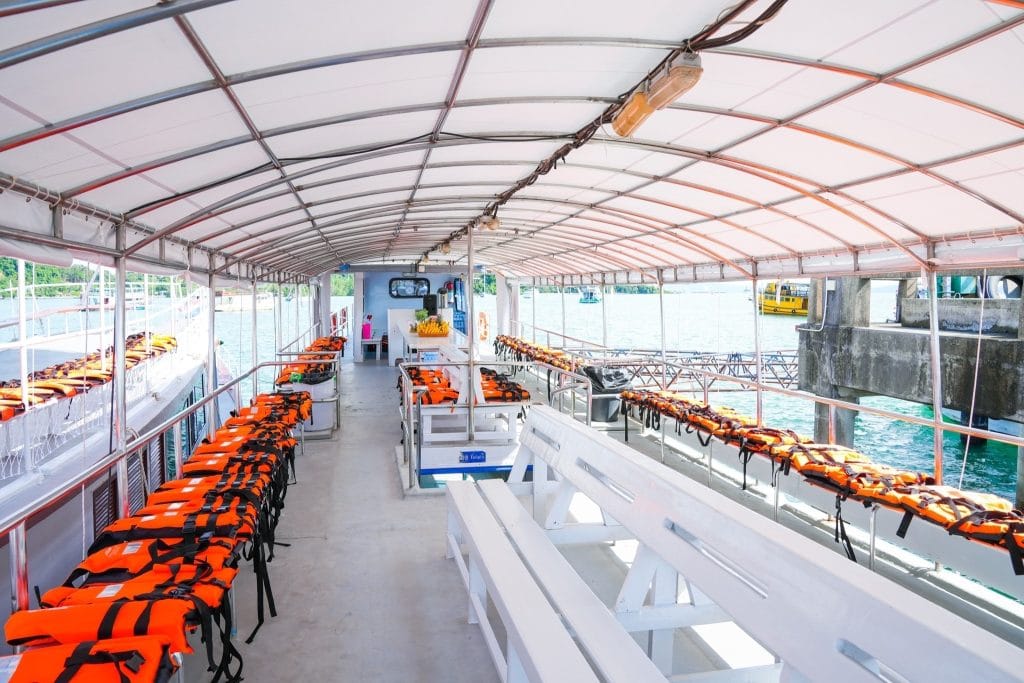 Rows of orange life jackets ready on the covered deck of a big tour boat in Phang Nga Bay