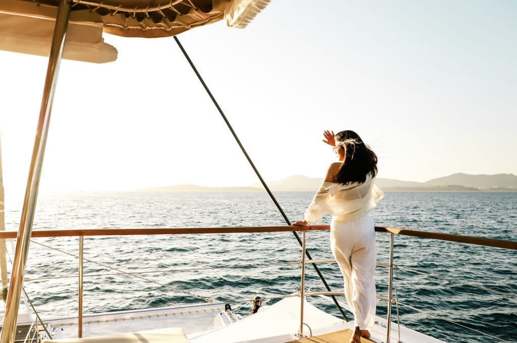 Woman leaning on the rail of a sailing yacht in warm golden evening light off Phuket