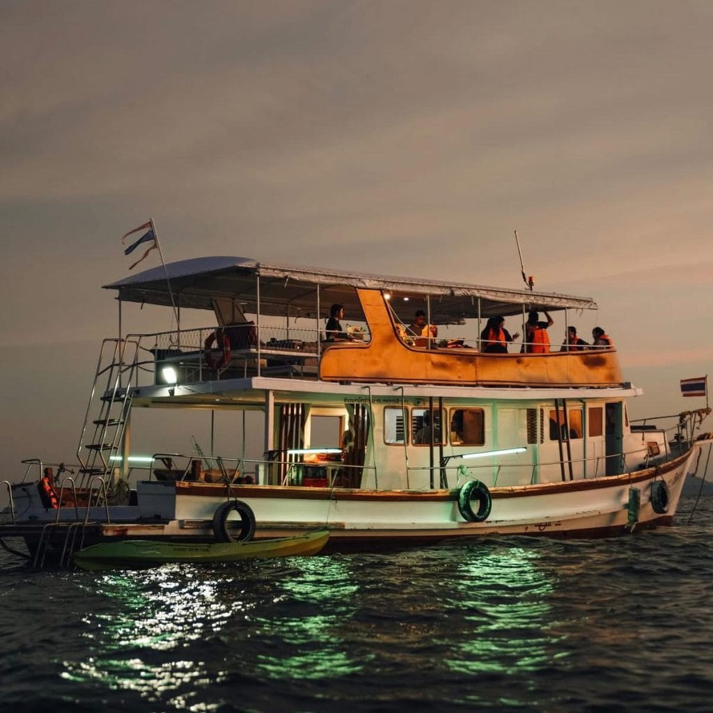 Traditional big boat lit up at dusk on Phang Nga Bay during a sunset dinner cruise